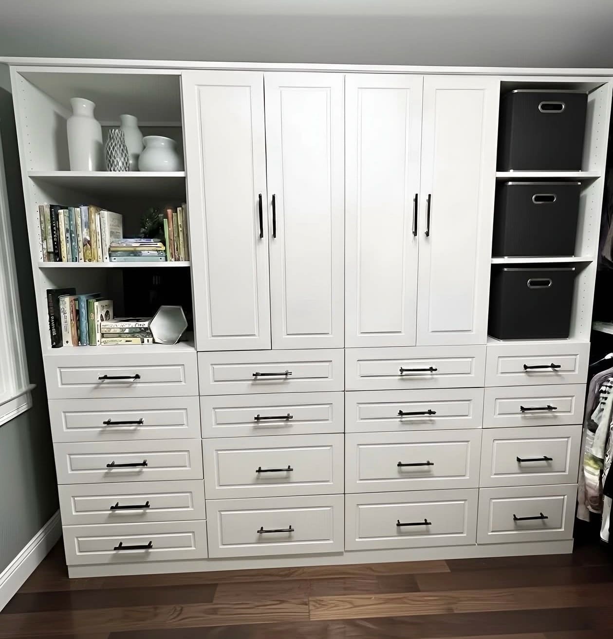 White built-in wardrobe with sixteen soft-close drawers, tall cupboards above and open shelving either side for books and baskets