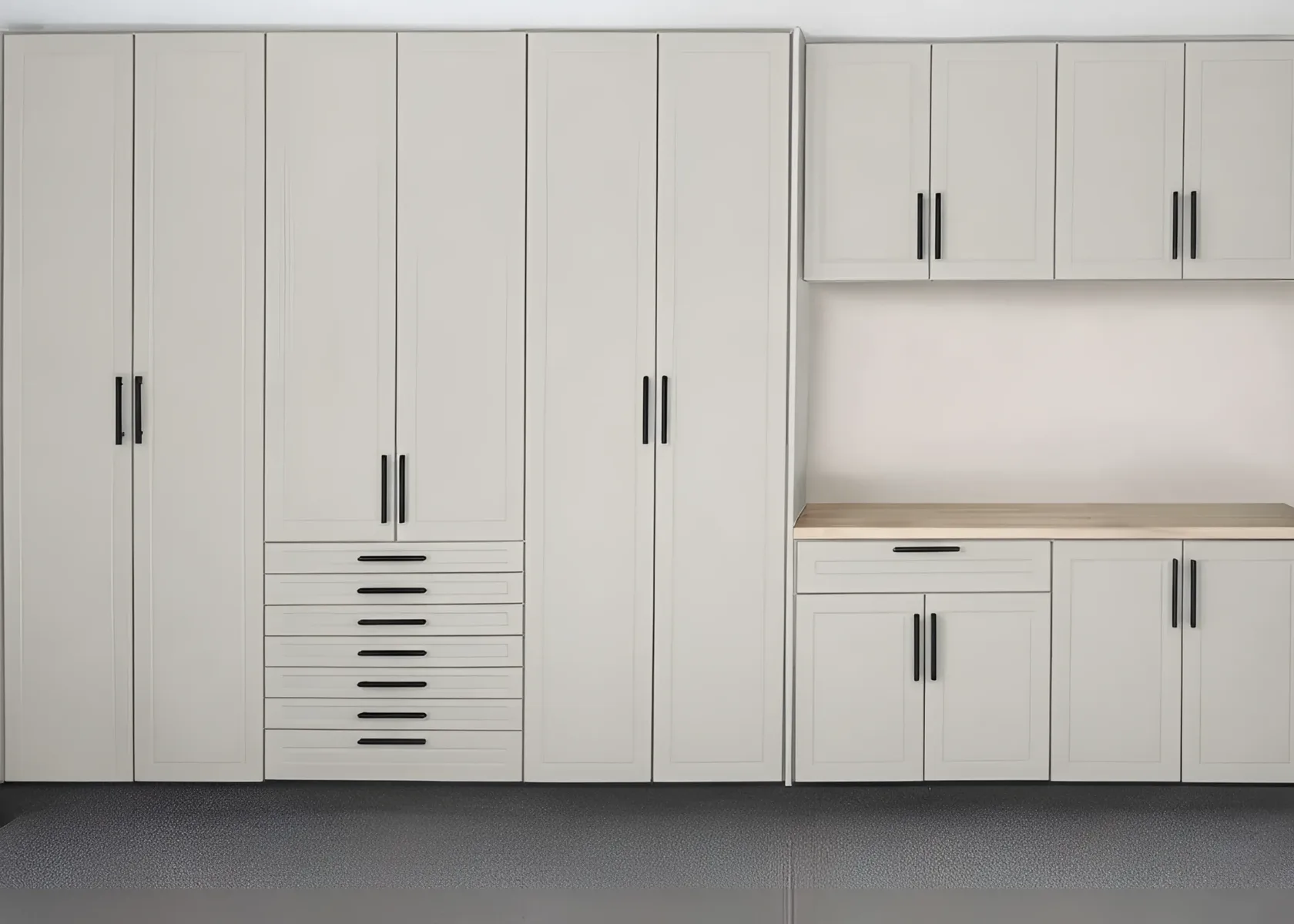 Cream shaker garage cabinets along a wall — three full-height units, a bank of seven drawers, upper wall cabinets and a butcher-block workbench over a base run