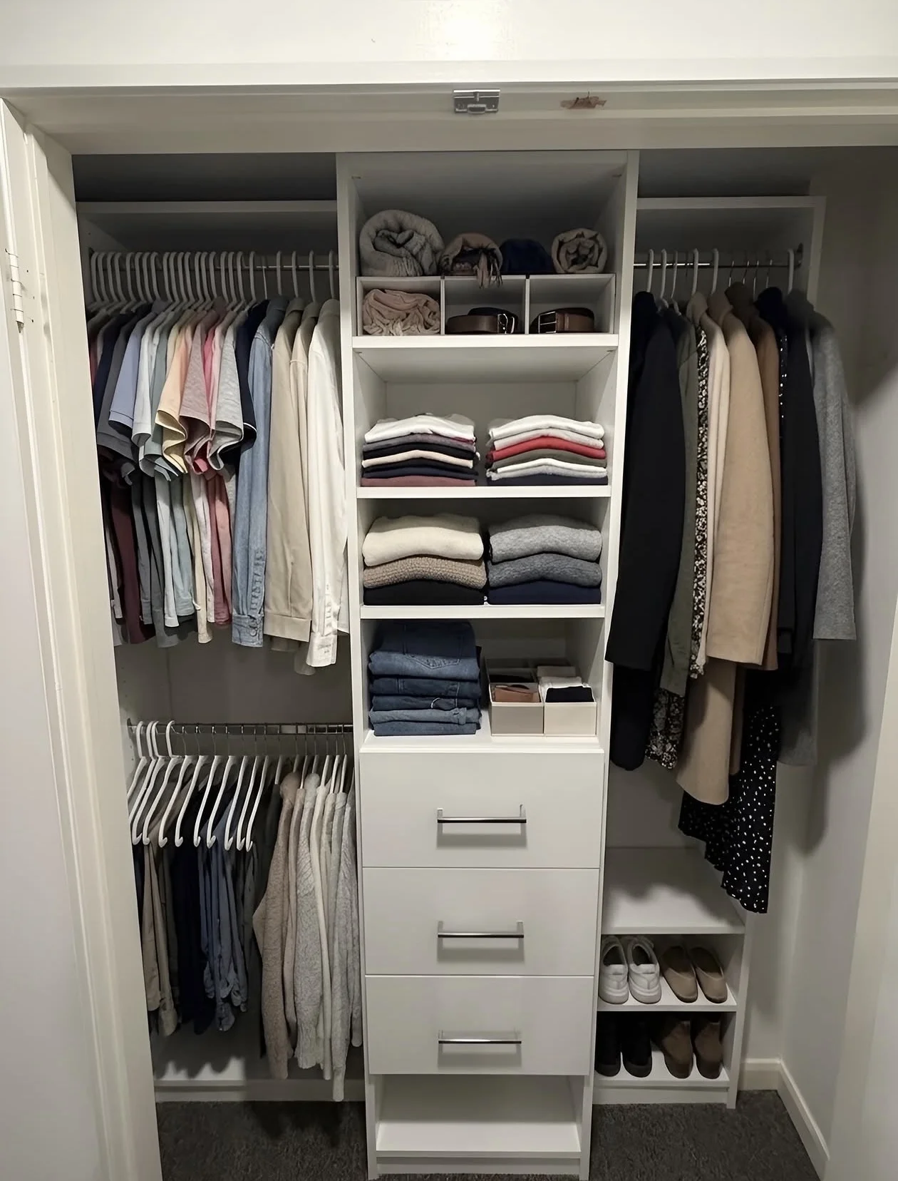 Reach-in closet with two levels of hanging, folded shelving and a central drawer bank, built by Closet Form in Toronto