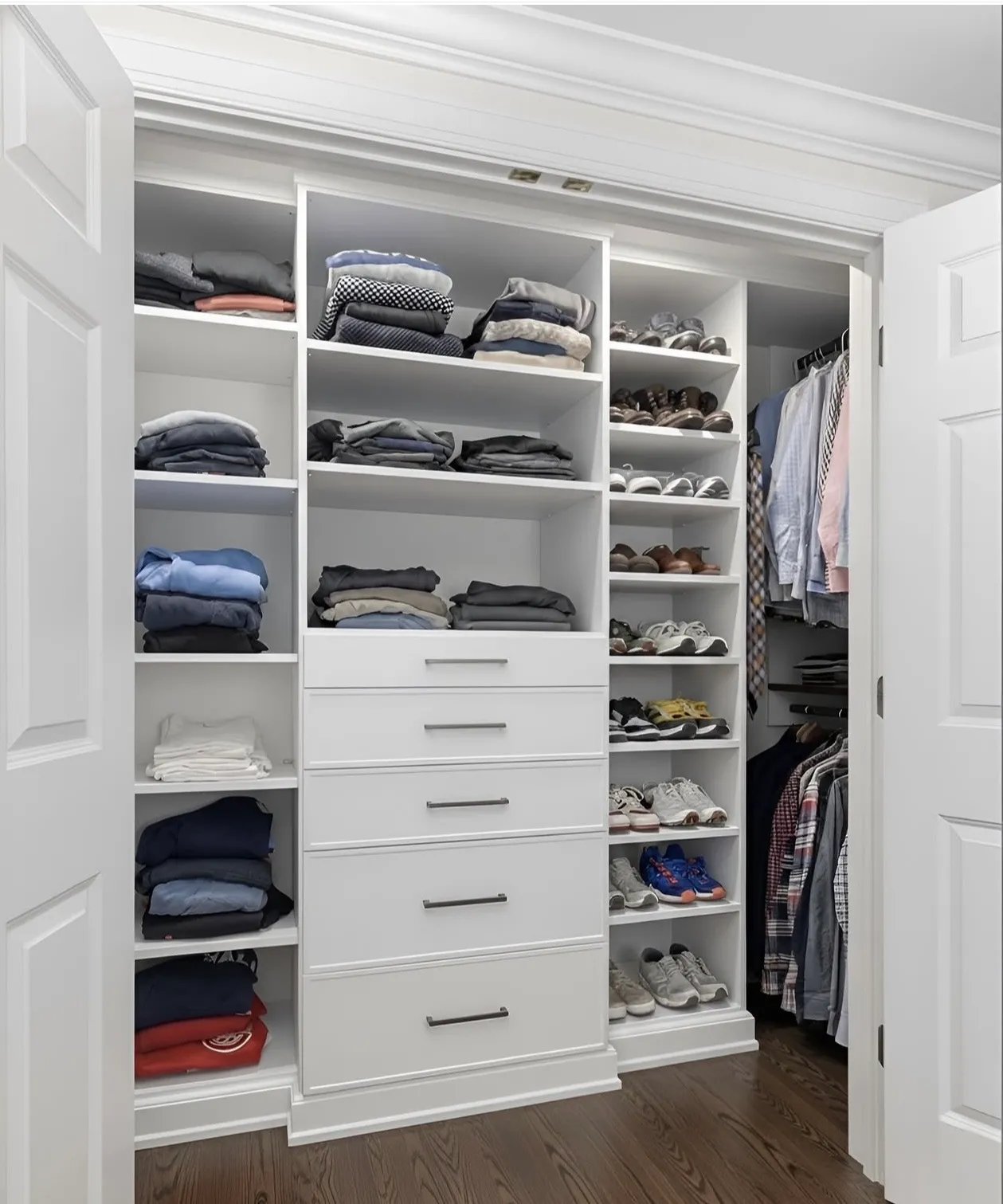 A white reach-in closet behind panelled doors, a five-drawer tower under folded shelving, shoe shelves to the right and hanging beyond