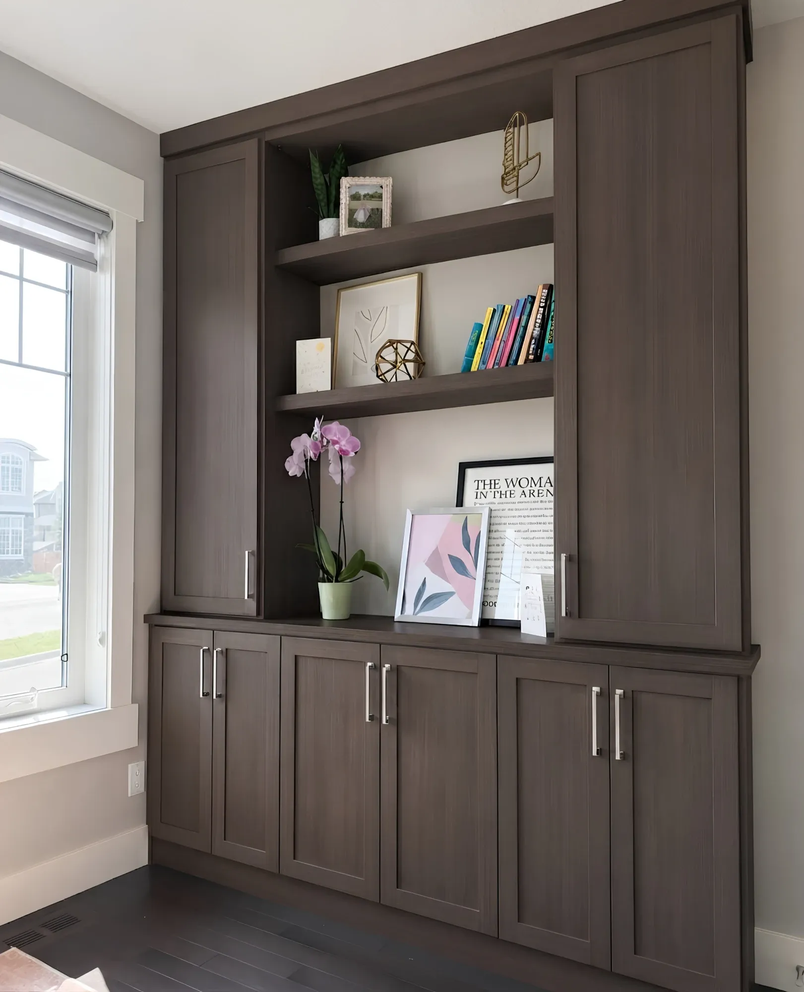 A walnut built-in beside a window, open display shelving between two full-height cupboards over a run of shaker doors