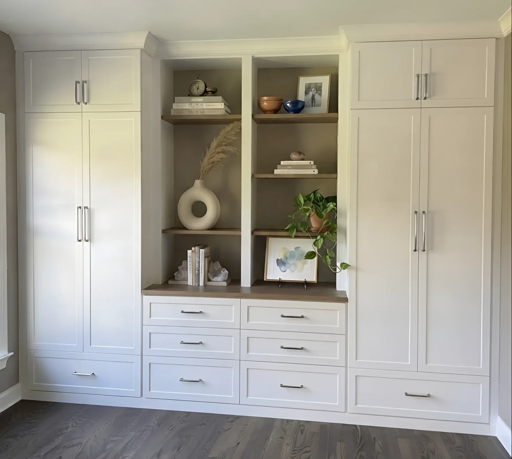A cream shaker wardrobe wall in a Richmond Hill bedroom, a full-height cupboard at each end and open oak shelving over six drawers down the middle