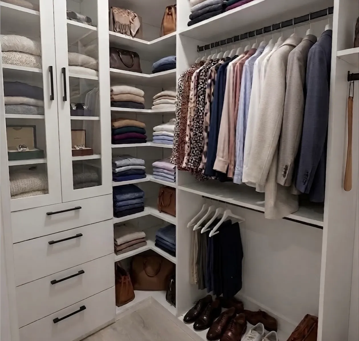 A white condo walk-in built into a corner, shelving carried up both walls with double hanging on the right and shoes on the floor of the long-hang bay