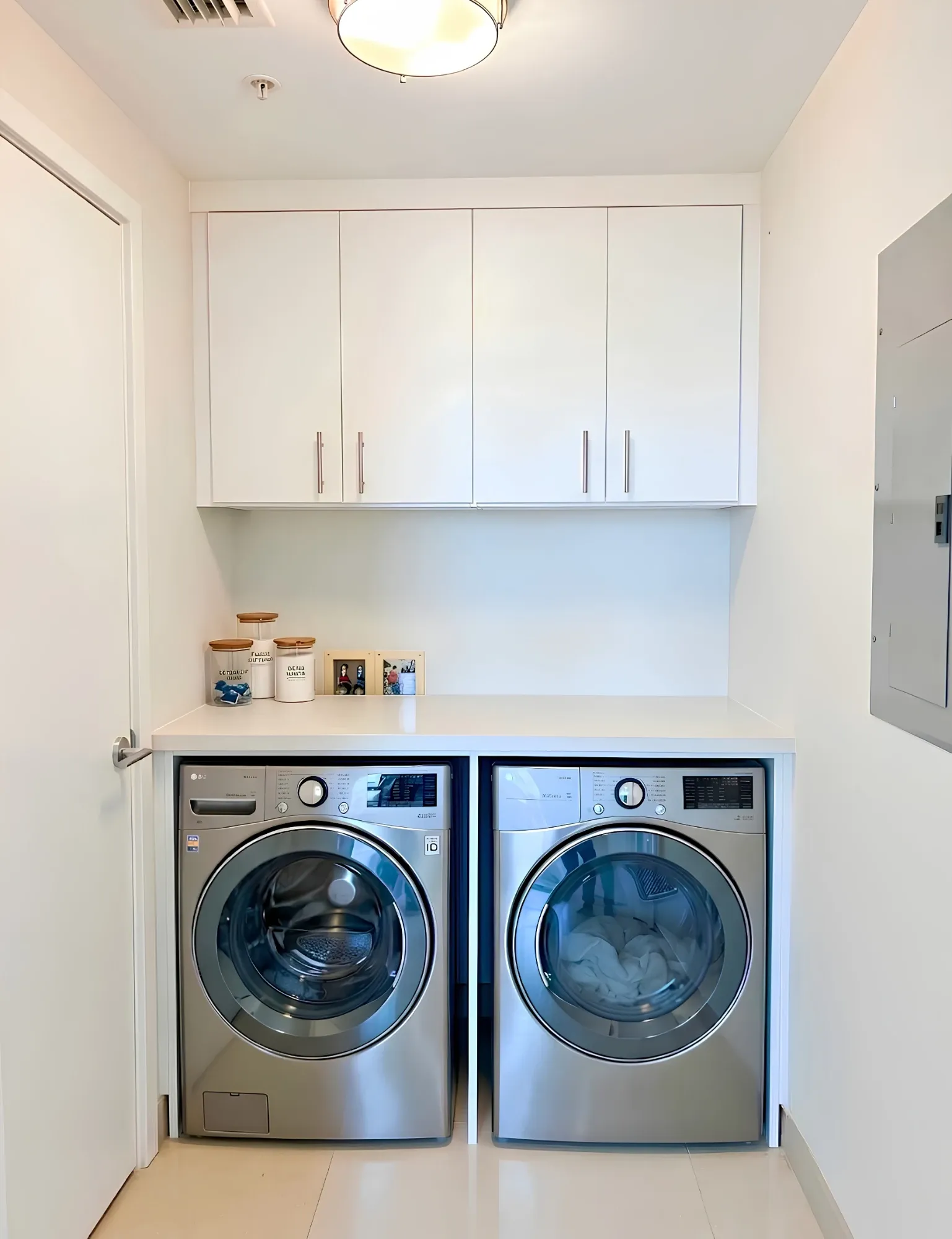 A white laundry run with a counter carried over the washer and dryer and closed cabinets above it