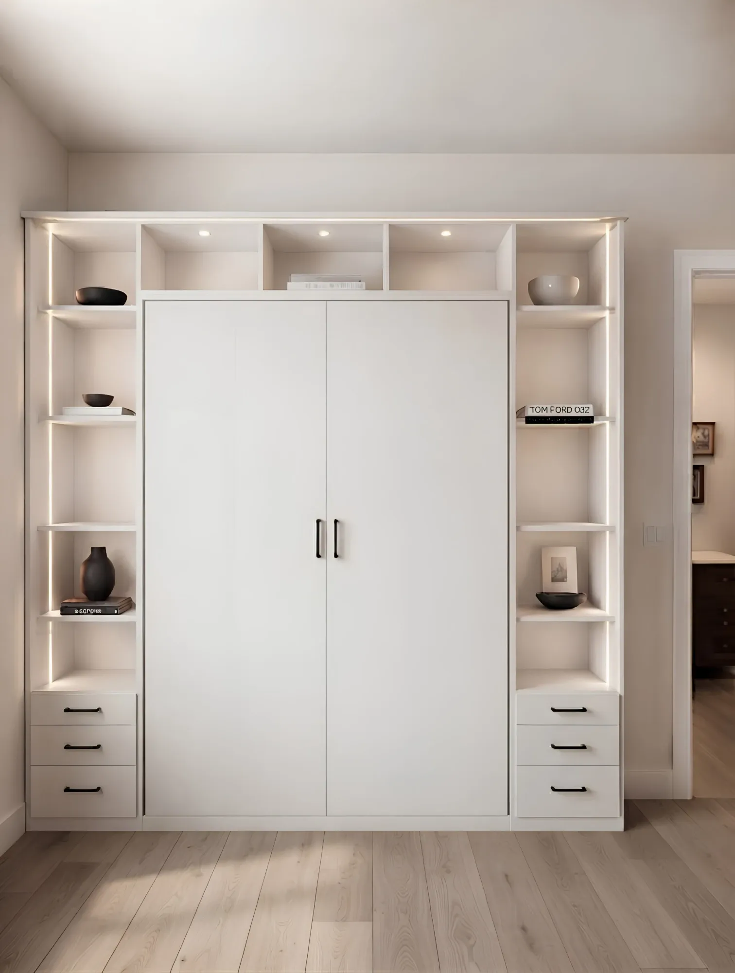 A white wall bed closed into its cabinet, lit display shelving up both sides and three drawers at the foot of each tower