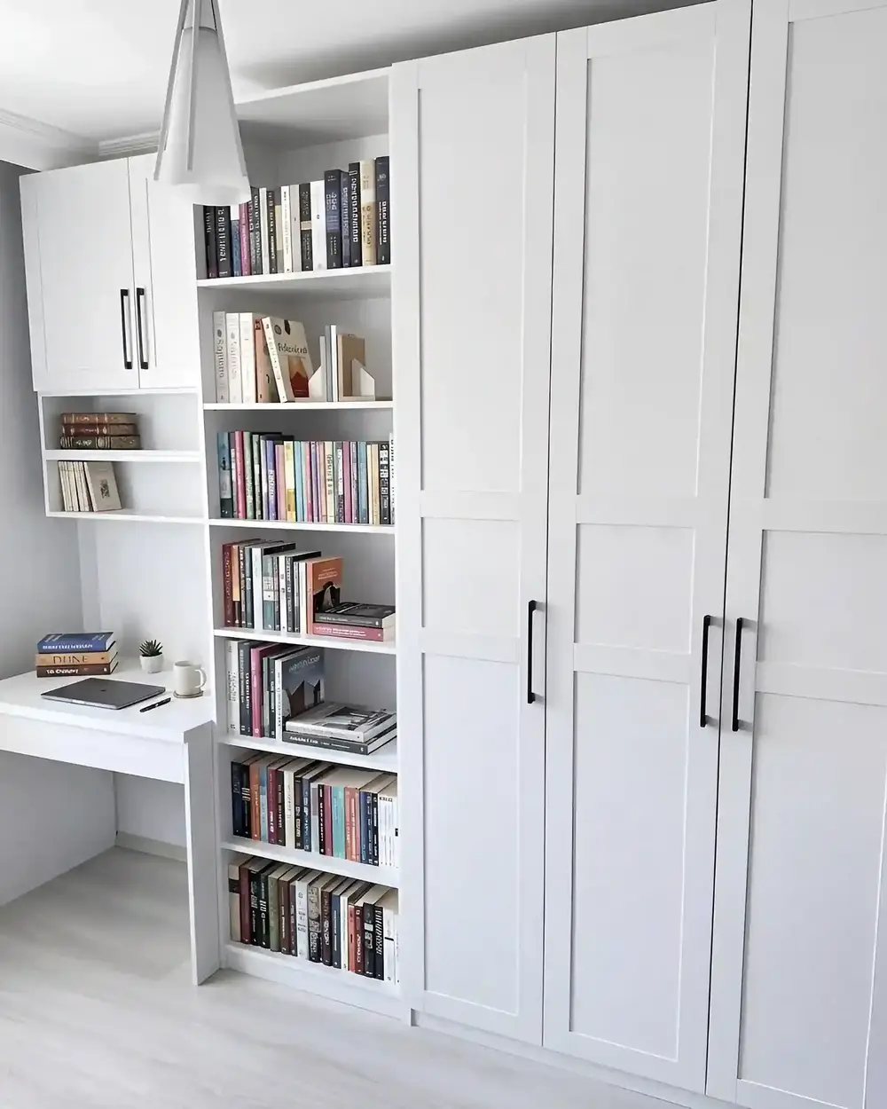 A white built-in home office with a desk between bookshelves and full-height cabinets