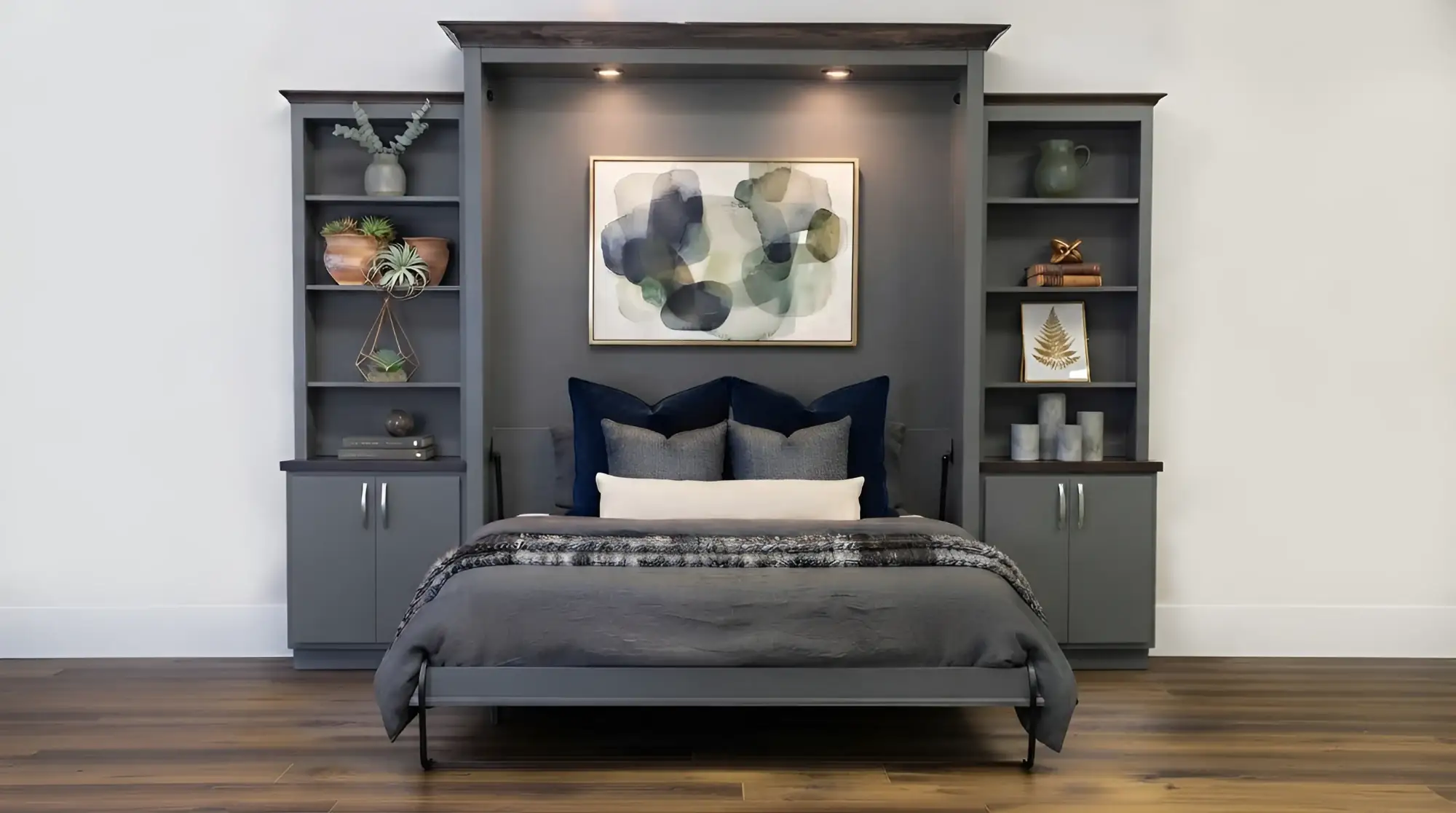 Custom grey murphy bed open in a Toronto bedroom, with open display shelving and cabinet bases either side and downlights set into the bridge above